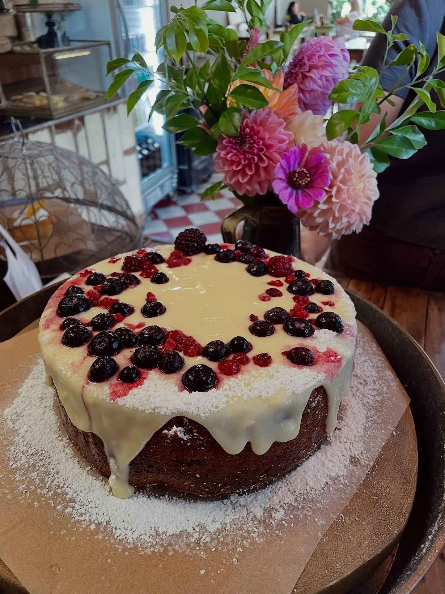 Berry cake beside fresh flowers at the counter