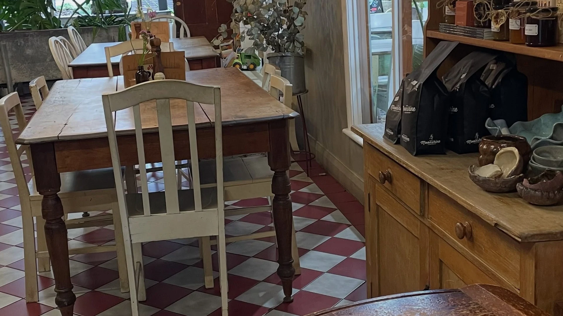The café's old timber counter framed by flowers, greenery and checkerboard floor