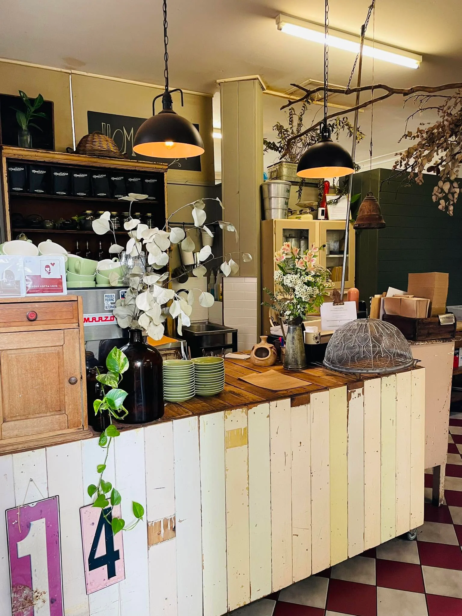 The timber counter, hanging greenery and checkerboard tiles